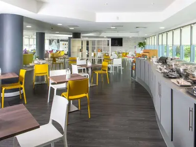 a restaurant with yellow chairs and tables and a counter at ibis Styles Haydock in Haydock