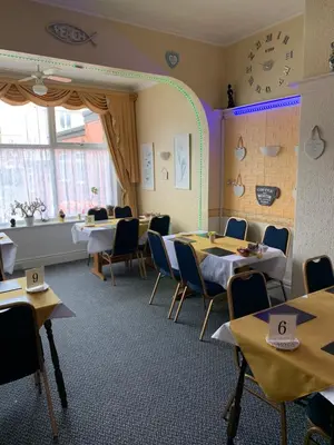 a dining room with tables and chairs and a clock at The Croydon in Blackpool