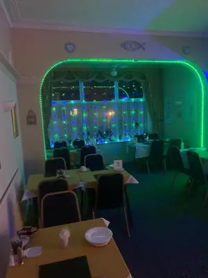 a dining room with tables and chairs and a green lighting at The Croydon in Blackpool