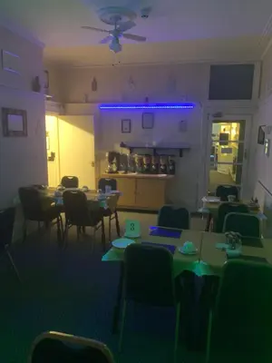 a dining room with tables and chairs and purple lights at The Croydon in Blackpool
