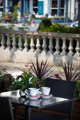 two cups of coffee sitting on a table in front of a fence at The Lord Street Hotel; BW Signature Collection in Southport