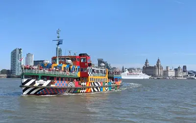 a colorful boat on the water with a city in the background at In Our Liverpool Home Sleeps 5 in 2 Double & 1 Single Bedrooms in Liverpool