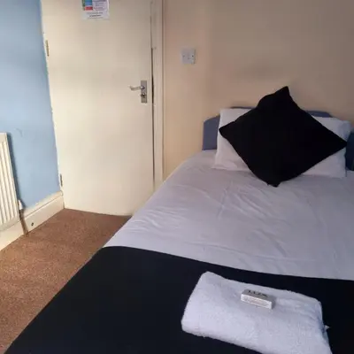 a bedroom with a white bed with a black pillow at The New Osterley Hotel in Blackpool