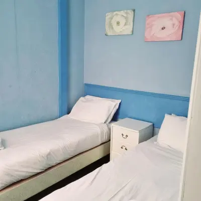 two twin beds in a room with blue walls at The New Osterley Hotel in Blackpool