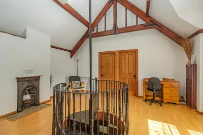 a room with a fireplace and a desk and a chair at Southport Coach House in Southport