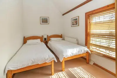 two twin beds in a room with a window at Southport Coach House in Southport