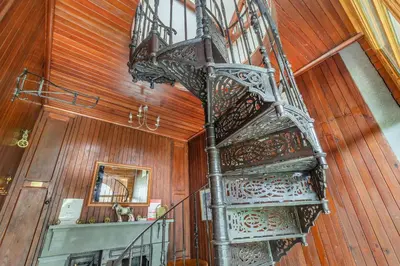 a metal spiral staircase in a room with wooden walls at Southport Coach House in Southport