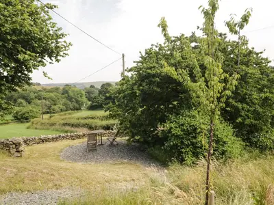 a bench next to a large bush in a field at Lane Head in Grange Over Sands