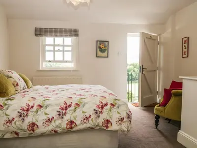 a bedroom with a bed with a floral bedspread at Lane Head in Grange Over Sands