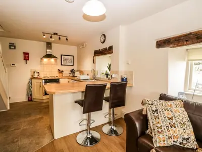a kitchen and living room with a counter and chairs at Lane Head in Grange Over Sands