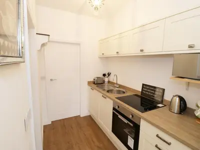 a kitchen with white cabinets and a sink and a stove at The Goose Shed in Thornton