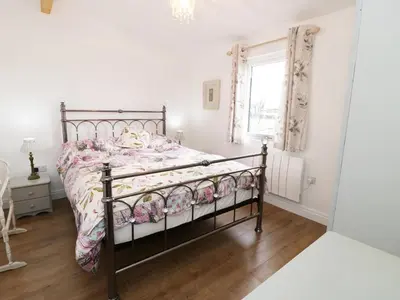 a bedroom with a bed with a comforter and a window at The Goose Shed in Thornton