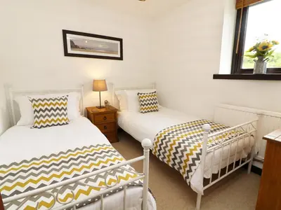 a bedroom with two beds and a window at The Hayloft in Grange Over Sands