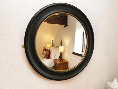 a mirror hanging on a wall with a bedroom at The Hayloft in Grange Over Sands