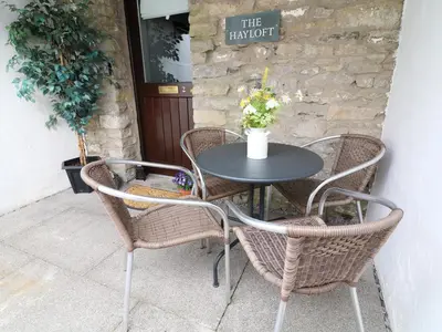 a table with three chairs and a table with flowers at The Hayloft in Grange Over Sands