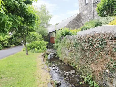 a stream next to a wall next to a street at The Hayloft in Grange Over Sands