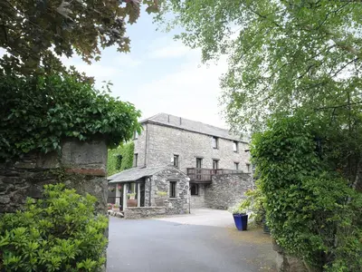 an external view of a stone building with a driveway at The Hayloft in Grange Over Sands