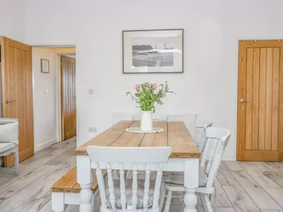 a dining room with a wooden table and white chairs at Driftwood Cottage Roa Island Piel Island in Barrow in Furness