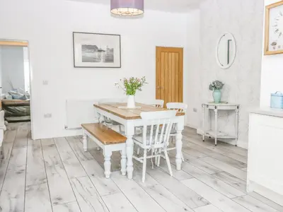 a white dining room with a table and chairs at Driftwood Cottage Roa Island Piel Island in Barrow in Furness