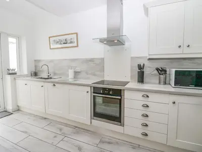 a white kitchen with a sink and a stove at Driftwood Cottage Roa Island Piel Island in Barrow in Furness