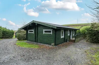 a green tiny house on a gravel road at Elm Lodge in Ulverston
