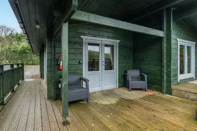 a green house with two chairs and a door at Elm Lodge in Ulverston