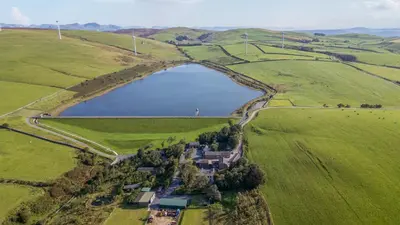 an aerial view of a house in a field next to a lake at Elm Lodge in Ulverston
