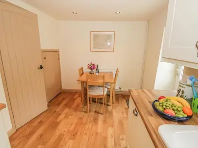 a kitchen with a table with a bowl of fruit at Herdwick Cottage in Grange Over Sands