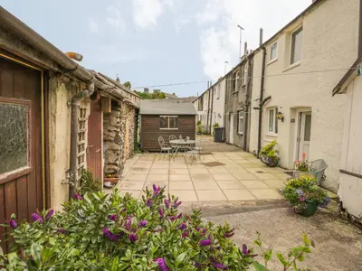 a courtyard of a house with a table and chairs at Herdwick Cottage in Grange Over Sands