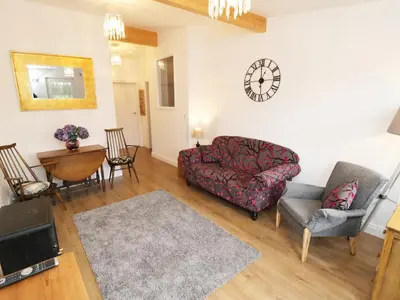 a living room with a couch and chairs and a clock at Foxes Den in Thornton