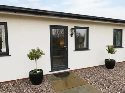 a white house with two potted trees in front of it at The Hen House in Thornton