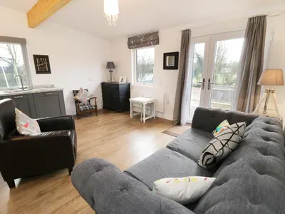 a living room with a gray couch and chairs at The Old Stables in Thornton
