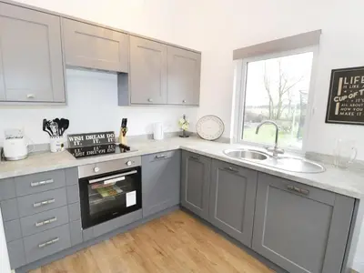 a kitchen with gray cabinets and a sink and a window at The Old Stables in Thornton