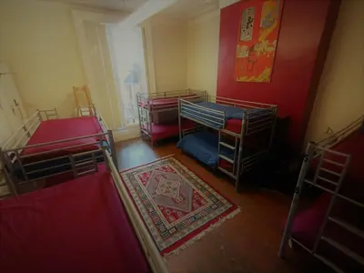 a room with three bunk beds and a red wall at Embassie Backpackers in Liverpool