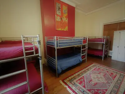 a room with three bunk beds and a rug at Embassie Backpackers in Liverpool