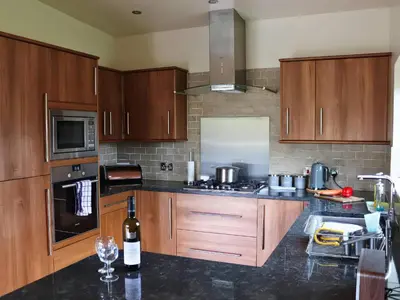 a kitchen with wooden cabinets and a bottle of wine at Boavista in Carnforth
