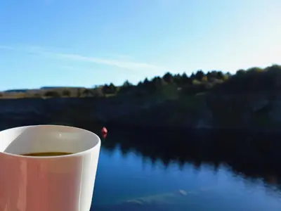 a cup of coffee sitting on a table next to a lake at Boavista in Carnforth