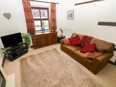 a living room with a couch and a television at 1 The Stables in Clitheroe