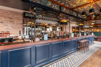a bar with blue walls and bar stools at Offshore - The Inn Collection Group in Lytham St Annes