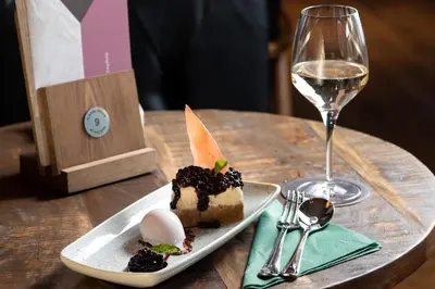 a piece of cake on a plate next to a glass of wine at Offshore - The Inn Collection Group in Lytham St Annes