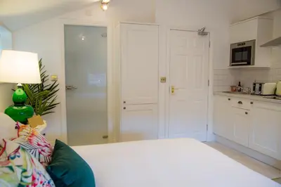 a bedroom with a white bed and a kitchen at Winckley Stays in Preston