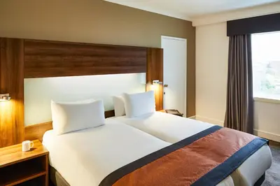 a bedroom with a large white bed and a window at Mercure St Helens in Saint Helens