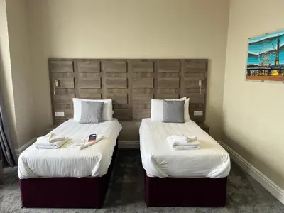 two beds in a hotel room with white sheets at Queens Hotel in Blackpool