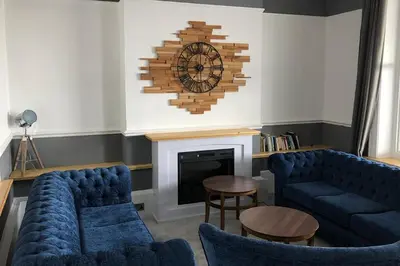 a living room with two blue couches and a fireplace at Queens Hotel in Blackpool
