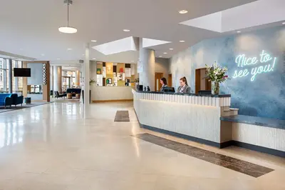 a lobby of a hospital with a woman sitting at a counter at Leonardo Hotel Liverpool in Liverpool