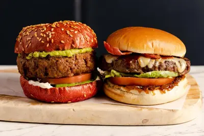 two hamburgers sitting on a wooden cutting board at Leonardo Hotel Liverpool in Liverpool