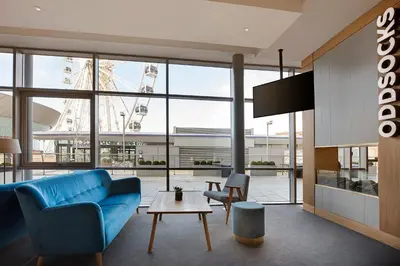 a living room with a blue couch and a table at Leonardo Hotel Liverpool in Liverpool