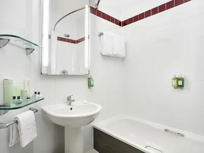 a white bathroom with a sink and a bath tub at Leonardo Hotel Liverpool in Liverpool