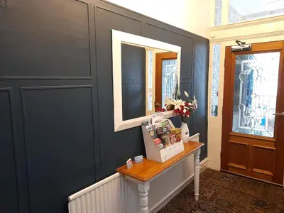 a hallway with blue walls and a table with a mirror at Phoenix Guest House in Blackpool