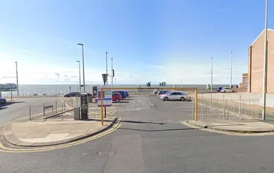 a parking lot with cars parked next to the beach at Phoenix Guest House in Blackpool